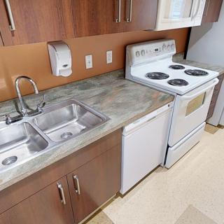 A kitchen with a double sink, stove, and wooden cabinets.