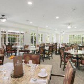 An elegant dining area with neatly arranged tables and chairs, illuminated by overhead lighting.