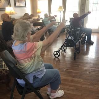 Elderly participants engage in a group exercise session, promoting health and social interaction.