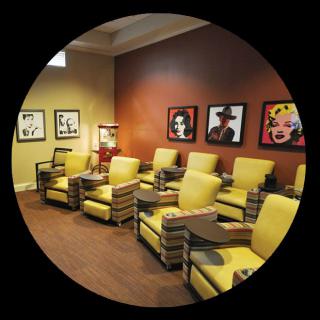 A stylish waiting room featuring bright yellow chairs and vibrant wall art.