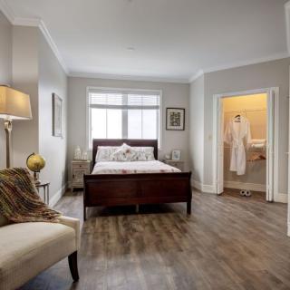 A modern bedroom interior with a cozy setup, featuring a bed, armchair, and decorative elements.
