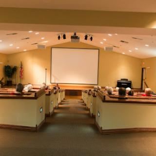 A spacious auditorium setup for presentations, featuring a large screen and arranged seating.