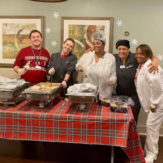 A group of cheerful individuals gathered around a buffet table, ready to serve a festive meal.