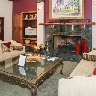 A cozy living room featuring a fireplace, elegant sofas, and a glass-top coffee table adorned with decorative items.