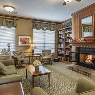 A cozy living room with a fireplace and bookshelf, featuring comfortable furniture and decorative touches.