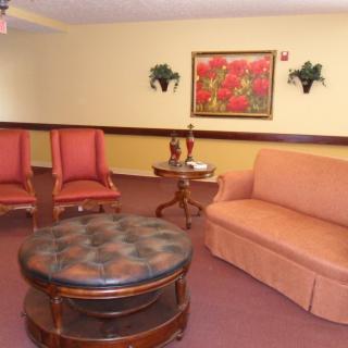 A cozy living room with a sofa, two chairs, and a round coffee table, accented by wall art and small decorative plants.