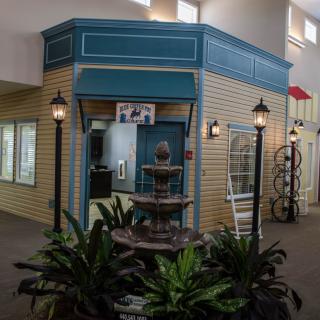 Indoor area with a decorative fountain and plants in front of a storefront.