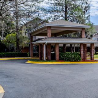 A parking area entrance surrounded by trees, featuring a covered driveway.