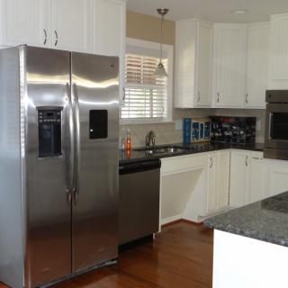 Modern kitchen with stainless steel appliances and white cabinets.