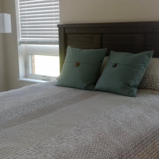 A neatly made bed with two green pillows in a bright bedroom.