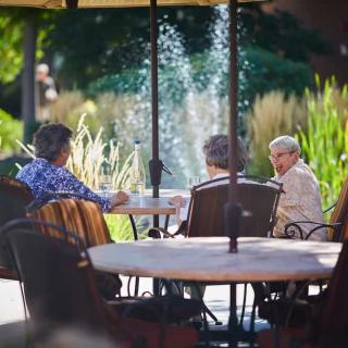 A group of people enjoying a conversation at an outdoor patio by a fountain.