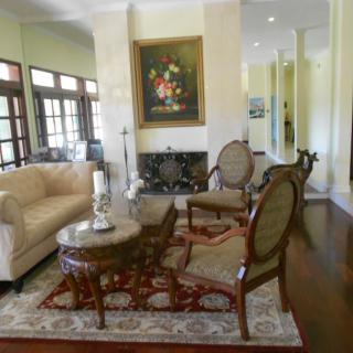 A traditional living room with elegant furniture and decor, featuring a sofa, chairs, coffee table, fireplace, and artwork.