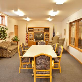 A comfortable meeting room with a central table and chairs, surrounded by sofas and bookshelves.