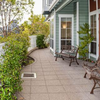A charming patio area with benches and lush greenery outside a house.