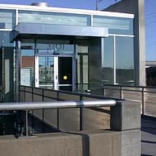 A modern building entrance with a glass facade and metal railings.