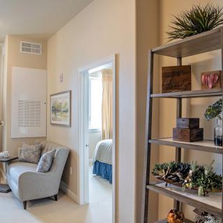 A cozy living room with a comfortable armchair and a decorative shelf filled with plants and decor items.