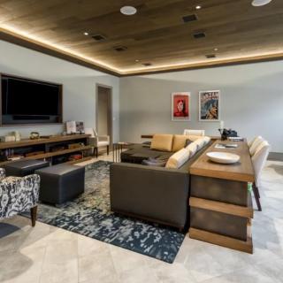 A modern living room with contemporary furniture, featuring a large sofa, a television, and decorative artwork.