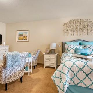 A cozy, well-decorated bedroom featuring a patterned bedspread and matching armchairs.