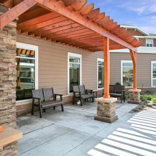 A stylish outdoor seating area featuring a wooden pergola and comfortable chairs, ideal for relaxing.