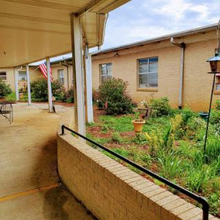 A serene courtyard view featuring a garden and pathway, with a flag in the background.