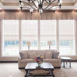 A beautifully designed living room featuring a comfortable sofa, elegant chandelier, and ample natural light from large windows.