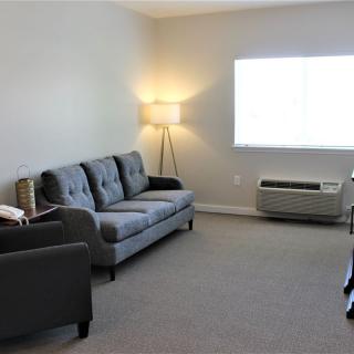 A simple and minimalistic living room with a sofa, lamp, and air conditioning unit.