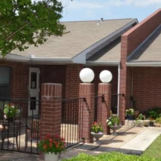 A brick residential house with a fenced yard and garden.
