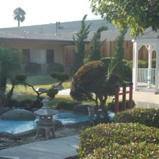 A picturesque garden featuring a serene water feature, neatly trimmed shrubs, and a charming gazebo.