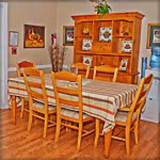 A cozy dining room with a wooden table, chairs, and a cabinet adorned with decorative items.
