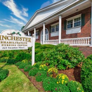 The exterior of Winchester Rehabilitation Center showcasing well-maintained landscaping and a clear sign.