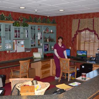 A reception area with a desk, computer, and a person standing in the workspace.