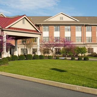 A modern hotel building with a well-maintained lawn and attractive landscaping at the entrance.