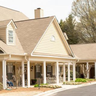 A suburban residential house with a spacious porch and surrounding trees.