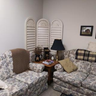 A cozy living room with floral-patterned furniture and a variety of decorative items.