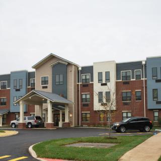 A modern apartment complex with a parking lot and multi-colored facade.