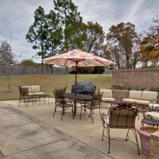 A spacious outdoor patio with seating and a large umbrella, surrounded by trees.