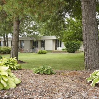 A tranquil garden scene with trees and a house in the background.