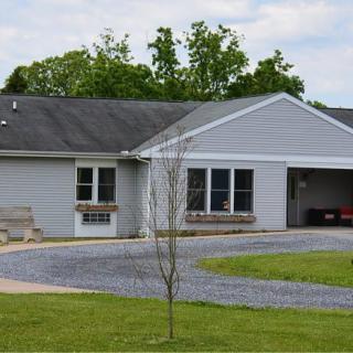 A suburban house with a driveway and garage, surrounded by a green lawn and trees.