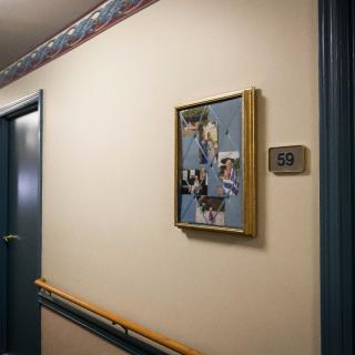 A hallway in a hospital with a framed artwork on the wall and a room number sign reading '159'.