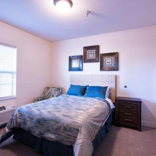A cozy bedroom with a neatly made bed and decorative artwork on the wall.