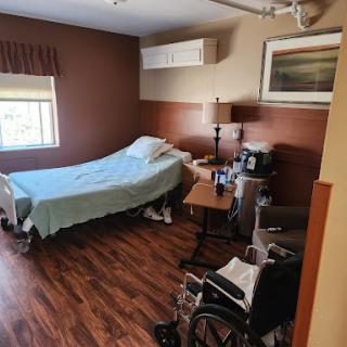 A cozy hospital patient room with a bed, wheelchair, and nearby medical supplies.