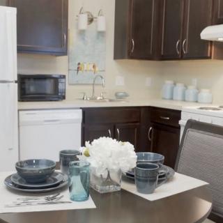 A modern kitchen with a neatly set dining table and dark wooden cabinets.