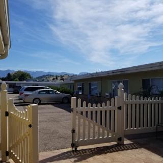 A view of a parking area surrounded by buildings and a mountain backdrop under a clear blue sky.