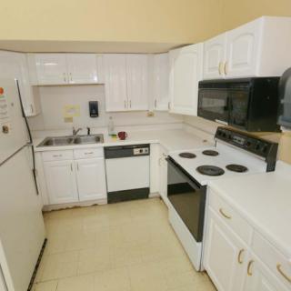 A compact kitchen with white cabinets and various appliances.