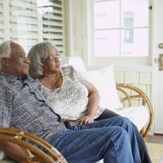 An elderly couple sitting together on a couch, enjoying a peaceful moment at home.