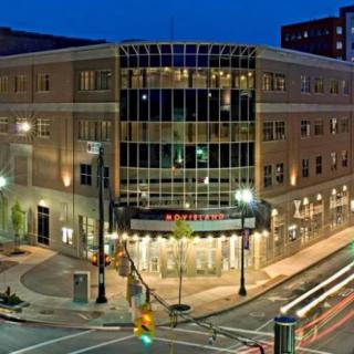 A modern building illuminated at night with street lights and light trails from passing vehicles.