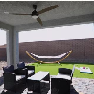 A cozy outdoor patio with modern furniture, a ceiling fan, and a hammock in the backyard.