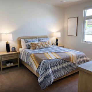 A cozy and modern bedroom with a neatly made bed, bedside tables, and two lamps.