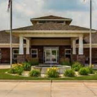 A front view of a building with columns, landscaping, and flags.