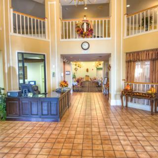 A spacious and warmly decorated lobby with a reception desk and tile flooring.